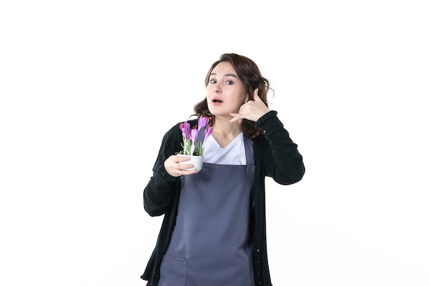 vooraanzicht jonge vrouw met paarse bloemen op lichte achtergrond bodem natuur uniform boom emotie tuin groen bloempot