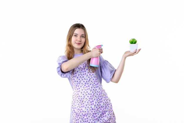 vooraanzicht jonge vrouw met spray en kleine groene plant op witte achtergrond bloem kleur tuin tuinman gras bush huis vrouw