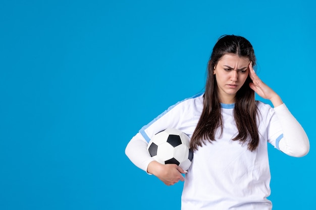 Vooraanzicht jonge vrouw met voetbal op blauwe muur