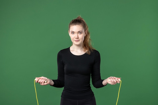 Vooraanzicht jonge vrouw trainen met springtouw op groene achtergrond kleur sport atleet yoga gezondheid lichaam vrouw gymnastiek