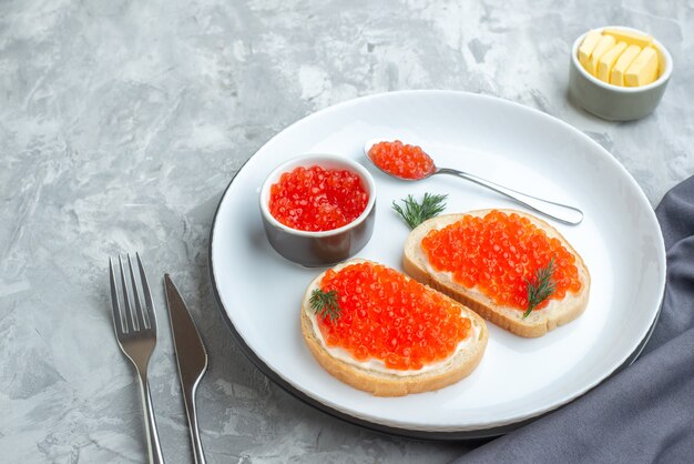 vooraanzicht kaviaar sandwiches binnen bord met bestek op witte ondergrond