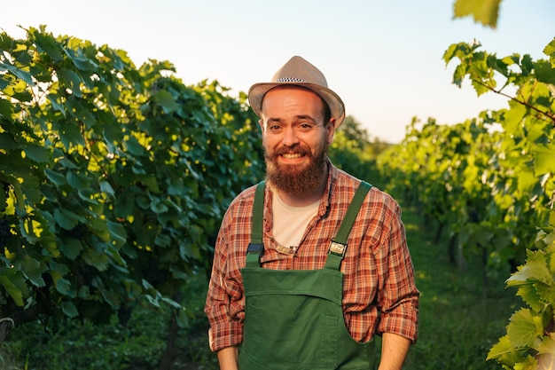 Vooraanzicht kijk naar de camera jonge boer man wijnmaker wijngaard arbeider lach houd handzakken rust