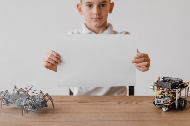 Foto vooraanzicht kleine jongen met een blanco papier