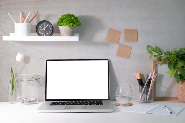 Vooraanzicht laptop wit leeg scherm kamerplant en briefpapier op witte tafel Thuisbureau