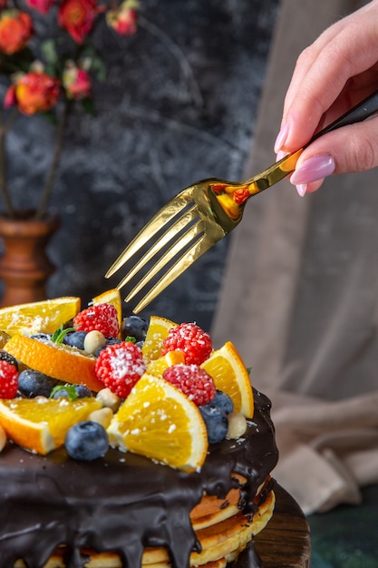 Vooraanzicht lekkere chocoladetaart met vers fruit op donkere muur