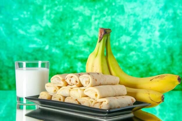 vooraanzicht lekkere gerolde pannenkoeken met bananen en melk op groene achtergrond fruit dessert ochtend zoete cake kleur suiker melk