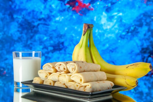 vooraanzicht lekkere gerolde pannenkoeken met bananen en melk op lichte achtergrond fruit ochtend zoete cake kleur melk dessert