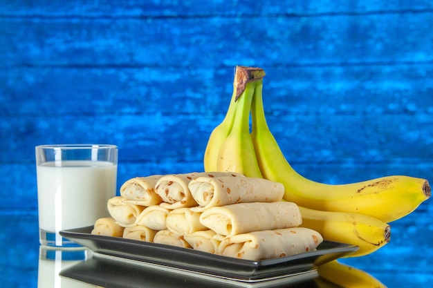 vooraanzicht lekkere gerolde pannenkoeken met bananen en melk op lichte achtergrond fruit ochtend zoete cake kleur suiker dessert