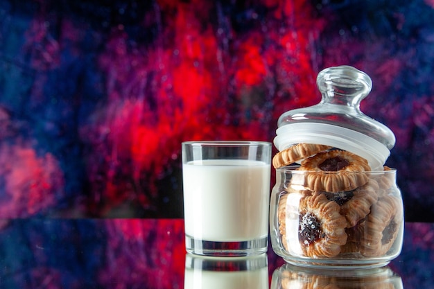 Vooraanzicht lekkere koekjes in blikje met glas melk op donkerblauwe achtergrond kleur suiker ontbijt cake ochtendmaaltijd zoet koekje dessert