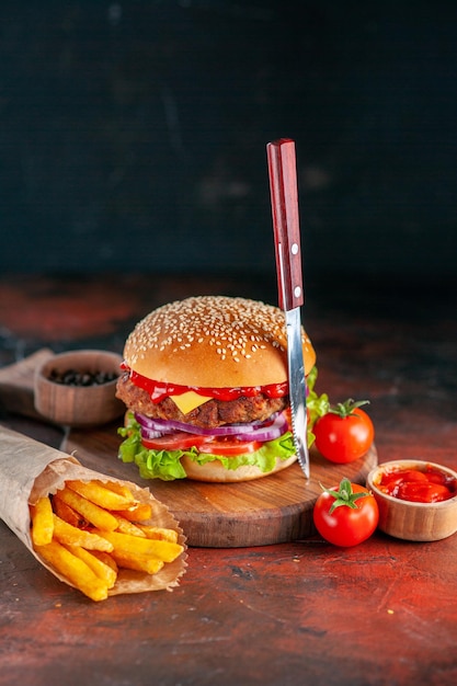 Vooraanzicht lekkere vlees cheeseburger met frietjes op donkere ondergrond