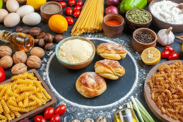 Vooraanzicht lekkere zoete broodjes rond eieren groenten pasta noten en kruiden op donkere achtergrond foto kleur maaltijd gezondheid voedsel dieet rauw gebak