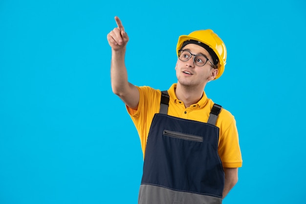 Vooraanzicht mannelijke bouwer in geel uniform op blauw