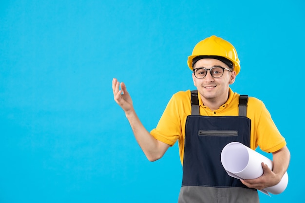 Vooraanzicht mannelijke bouwer in uniform met papieren plan op blauw