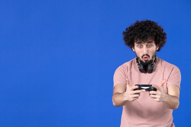 vooraanzicht mannelijke gamer die videogame speelt met gamepad blauwe achtergrond jeugd vreugde voetbal sofa virtueel winnend volwassen tiener