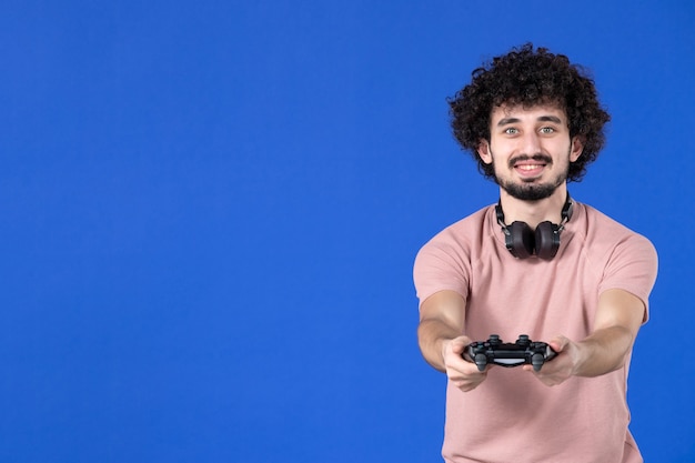 Vooraanzicht mannelijke gamer die videogame speelt met gamepad op blauwe achtergrond sofa virtuele vreugde speler tiener jong voetbal volwassen jeugd winnen