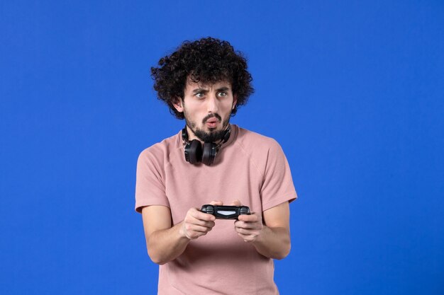 vooraanzicht mannelijke gamer die videogame speelt met gamepad op blauwe achtergrond virtuele volwassen video winnende speler jonge voetbaltiener