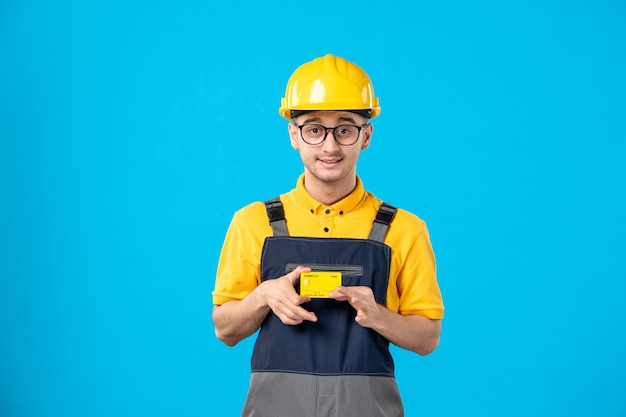 Vooraanzicht mannelijke werknemer in geel uniform met creditcard op een blauw