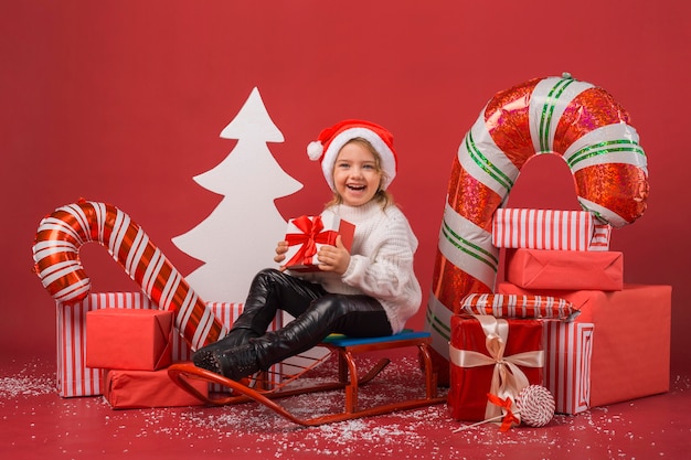 Foto vooraanzicht meisje omgeven door kerstcadeaus en elementen