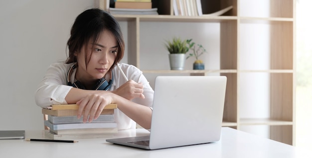 Vooraanzicht op jonge blanke vrouwenstudie voor de laptop thuis - lezingsboek van het meisje die examentest voorbereiden die online overleg hebben