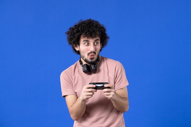 vooraanzicht opgewonden jonge man die videogame speelt met zwarte gamepad op blauwe achtergrond tiener jeugd winnende speler sofa volwassen virtuele vreugde voetbal