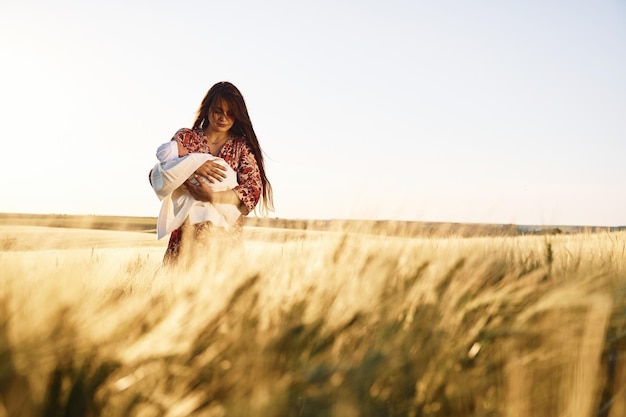 Vooraanzicht Prachtige vrouw is op het landbouwveld met haar pasgeboren baby