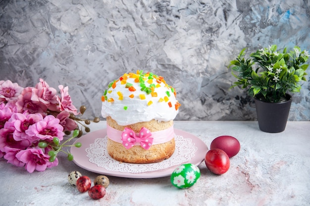 vooraanzicht smakelijke paascake met gekleurde eieren in plaat op wit oppervlak dessert zoete sierlijke Pasen kleurrijke taart