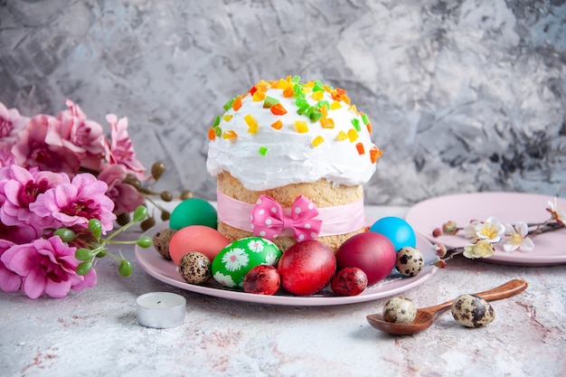 vooraanzicht smakelijke paascake met gekleurde eieren in plaat op wit oppervlak zoete taart paasdessert sierlijke lente