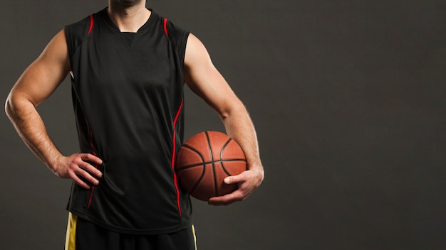 Foto vooraanzicht van basketbalspeler die en bal stellen houden