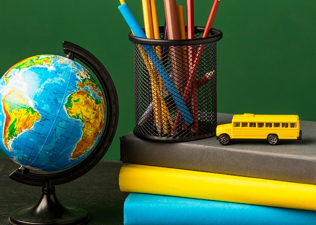 Foto vooraanzicht van bol met stapel boeken en schoolbus