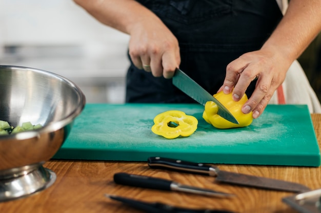 Vooraanzicht van chef-kok met schort die paprika snijden