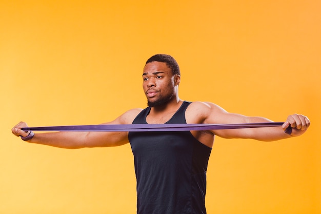 Foto vooraanzicht van de atletische man in gym outfit met weerstand band