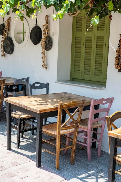 Vooraanzicht van de buitenkant van het kleine café Tafel en lege stoelen buiten bij de witte muur Toeristische plaatsen Typisch mediterraan restaurant een vakantieplaats in de zomer