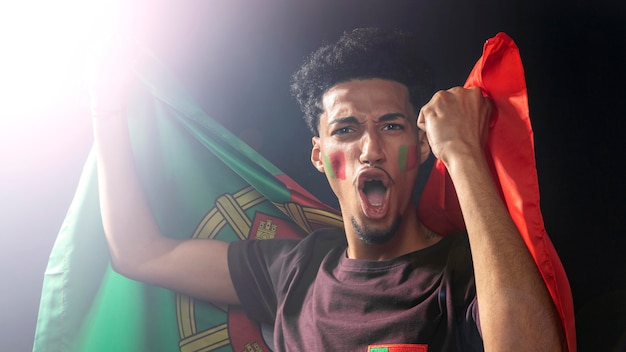 Foto vooraanzicht van de man die toejuicht en de vlag van portugal vasthoudt