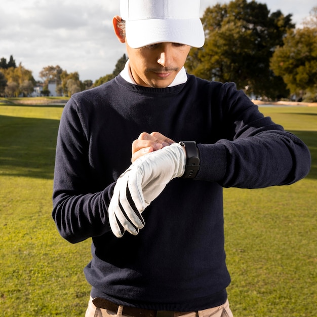 Foto vooraanzicht van de mens die zijn smartwatch op het golfgebied aanpast