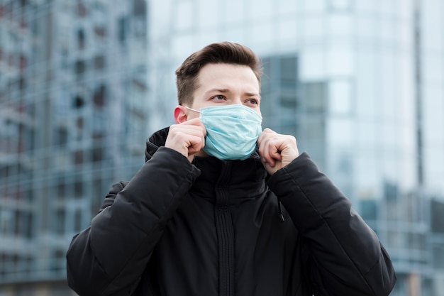 Foto vooraanzicht van de mens in de stad die medisch masker draagt