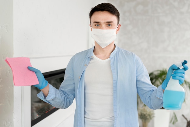 Foto vooraanzicht van de mens met de schoonmakende vloeistof van de gezichtsmaskerholding