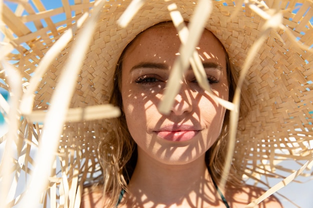 Vooraanzicht van een blanke vrouw met een strooien hoed, liggend op het strand en zonnebadend. Weekend strandvakantie, levensstijl en vrije tijd.