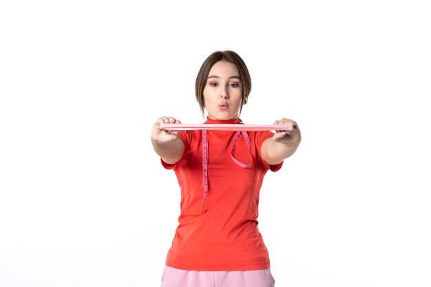 Vooraanzicht van een gefocust jong meisje in het opnieuw kleuren van een blouse die elastisch accessoire uitrekt op een witte achtergrond