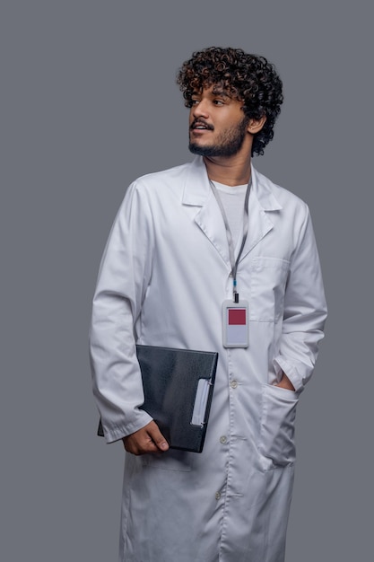Foto vooraanzicht van een gefocuste mannelijke arts die een identificatiebadge boven de laboratoriumjas draagt