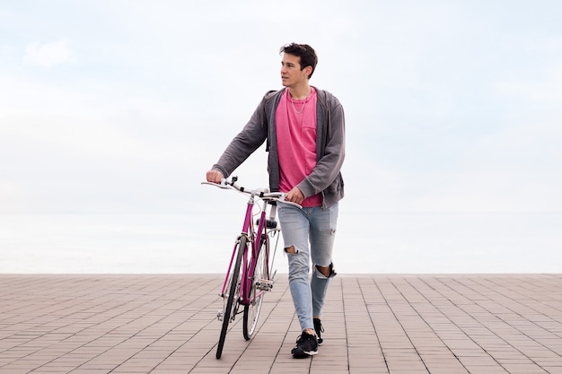Vooraanzicht van een jonge man die loopt en een fietsconcept van duurzaam transport duwt