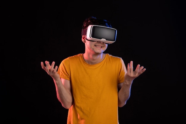Vooraanzicht van een jonge man die virtual reality speelt op de donkere muur