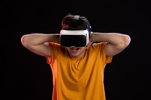 Vooraanzicht van een jonge man met een vr-headset op de donkere muur