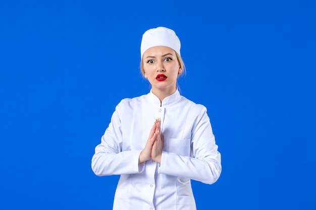vooraanzicht van flirt jonge verpleegster in wit medisch pak op blauwe achtergrond pandemische ziekte ziekenhuis covid- geneeskunde ziekte medicijn virus gezondheid