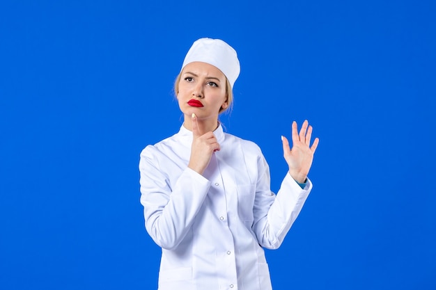 vooraanzicht van flirt jonge verpleegster in wit medisch pak op blauwe achtergrond pandemische ziekte ziekenhuisvirus covid-medicijn ziekte drug