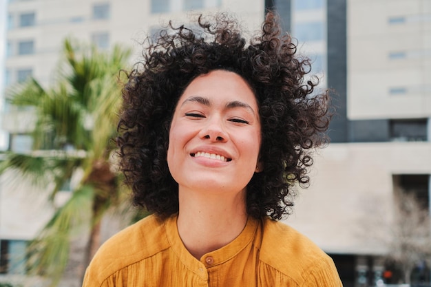 Vooraanzicht van gelukkige jonge Spaanse vrouw die lacht met krullend haar Close-up portret van cracy dame lachen en plezier maken