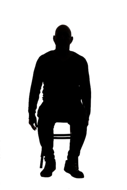 Vooraanzicht van het silhouet van een man die op een stoel zit en naar de camera kijkt