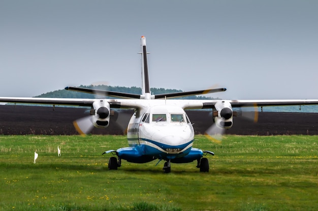 Vooraanzicht van het taxiën van een passagiersvliegtuig met turboprop op een landelijk vliegveld bij bewolkt zomerweer