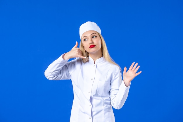 vooraanzicht van jonge verpleegster in medisch pak op blauwe muur