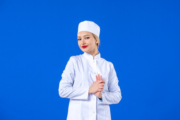 Vooraanzicht van jonge verpleegster in medisch pak op blauwe muur