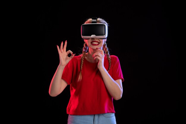 Vooraanzicht van jonge vrouw die virtual reality speelt op donkere muur